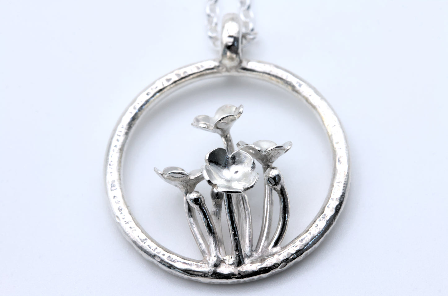 A pendant with multiple tiny flowers within a textured ring