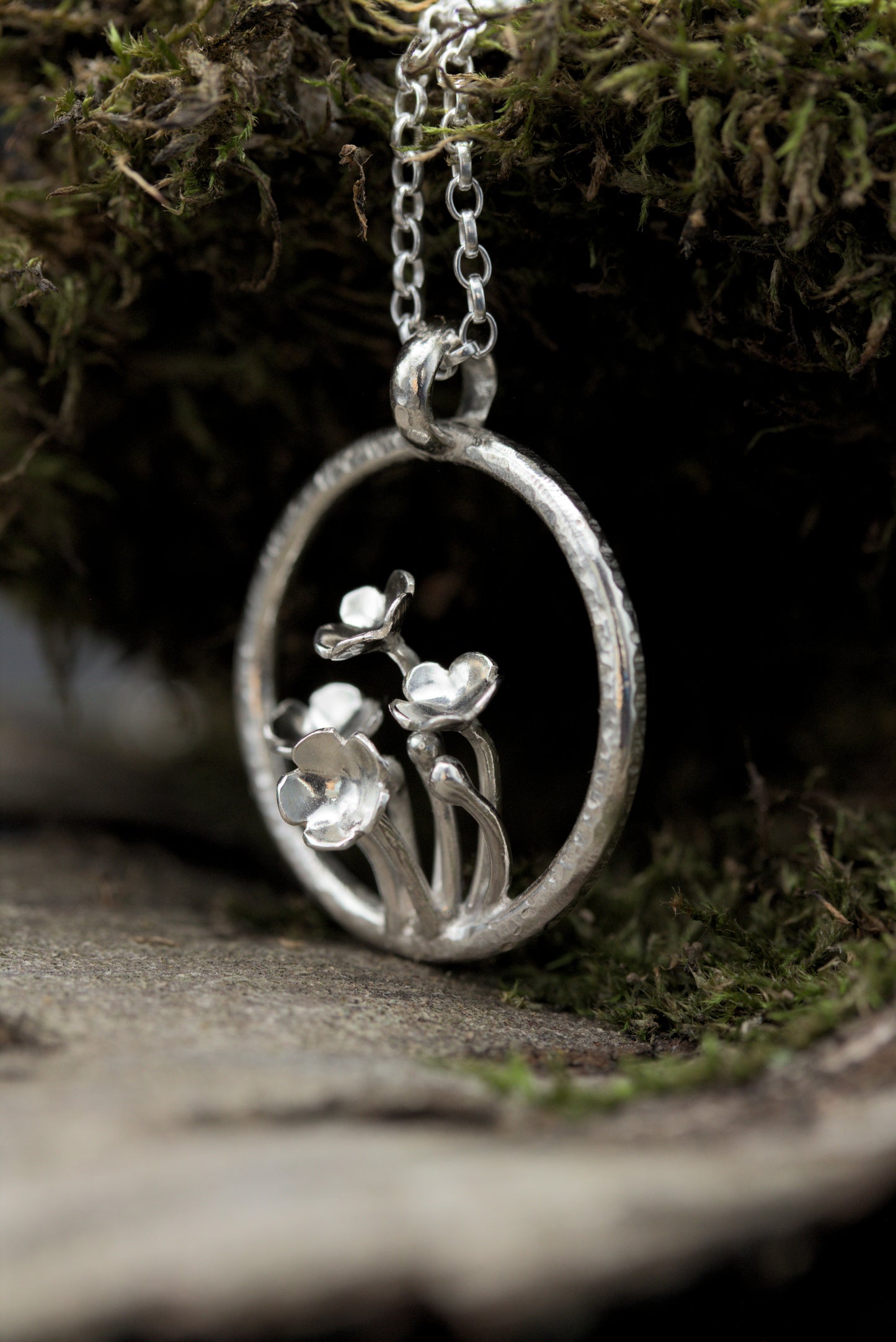 A pendant with multiple tiny flowers within a textured ring