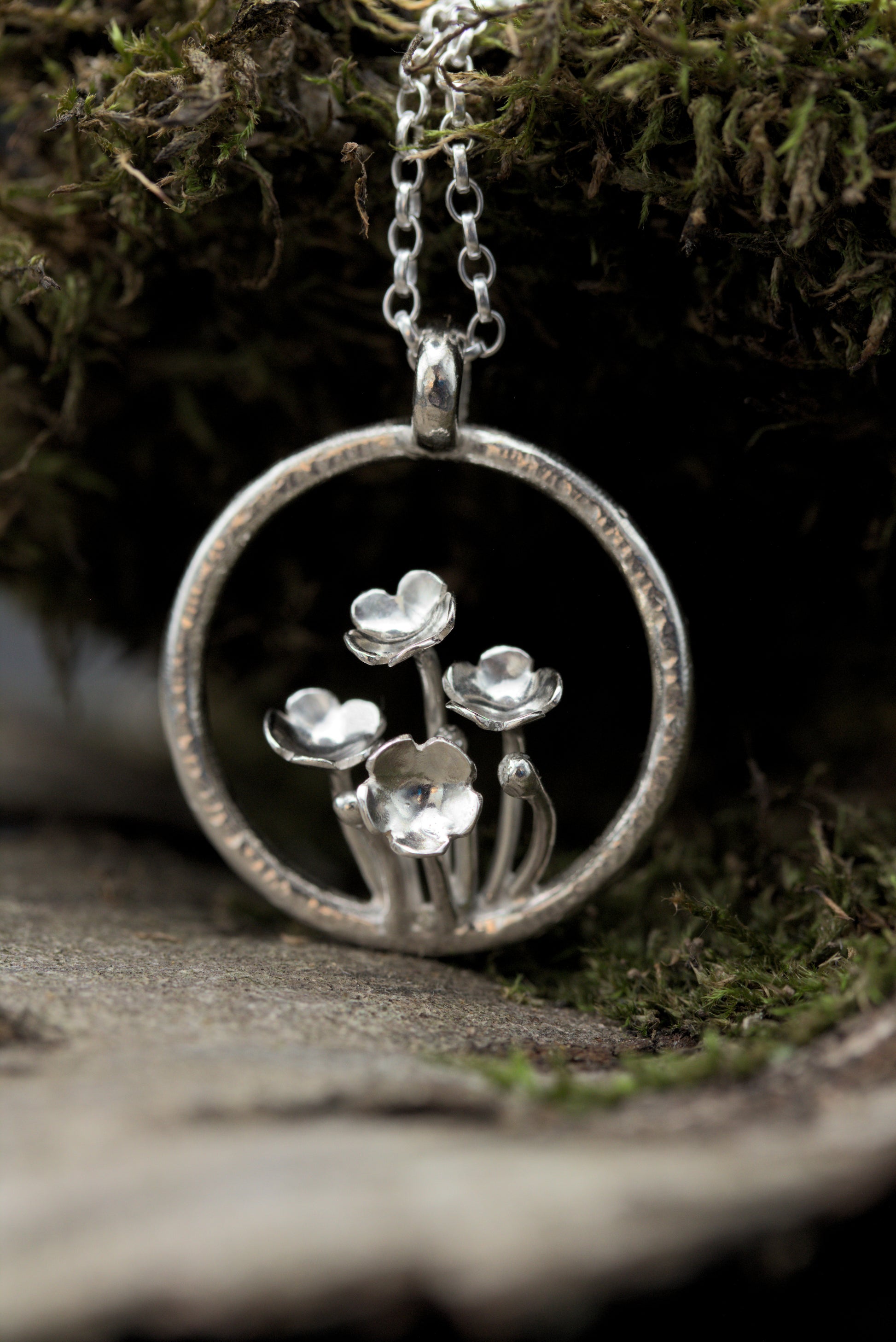 A pendant with multiple tiny flowers within a textured ring