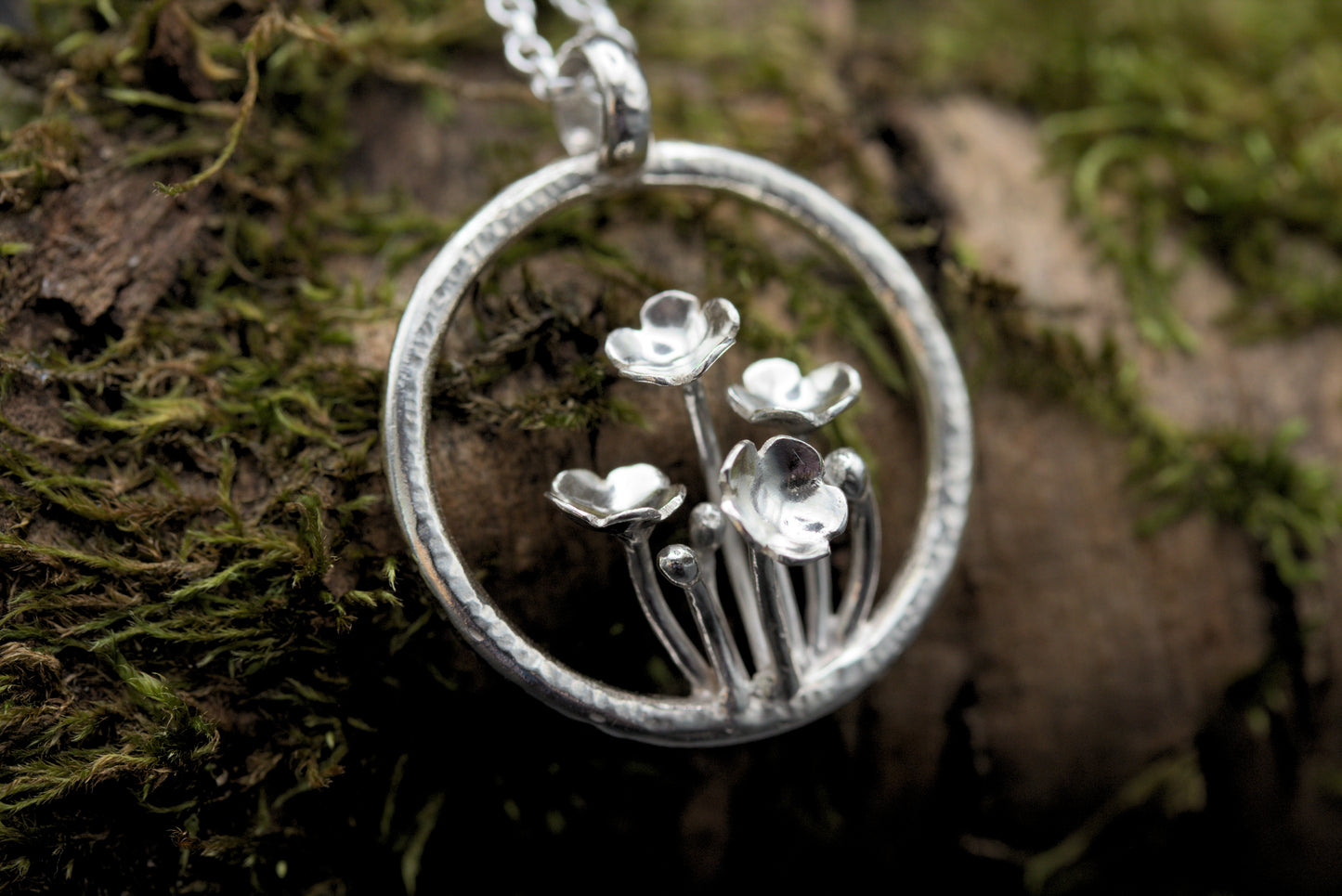 A pendant with multiple tiny flowers within a textured ring