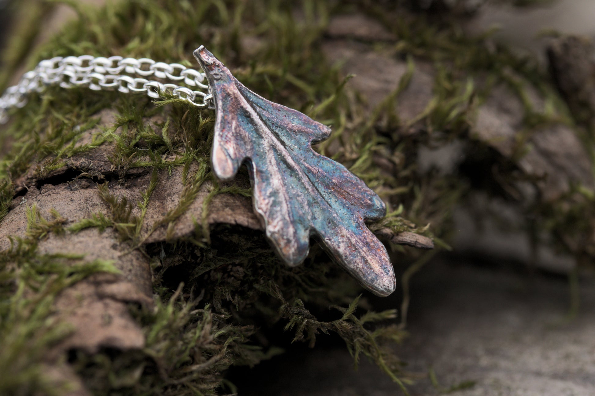 A small silver leaf pendant with colourful patina