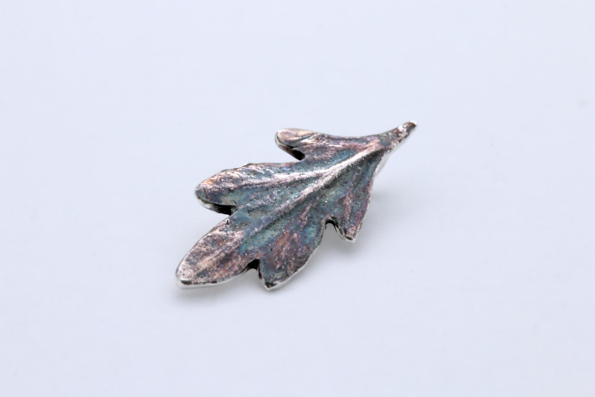 A small silver leaf pendant with colourful patina