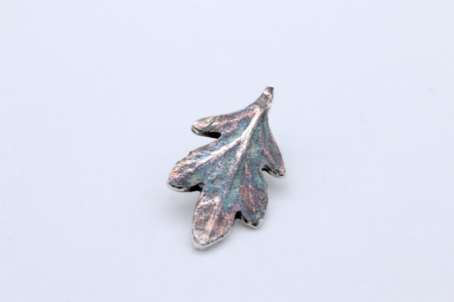 A small silver leaf pendant with colourful patina