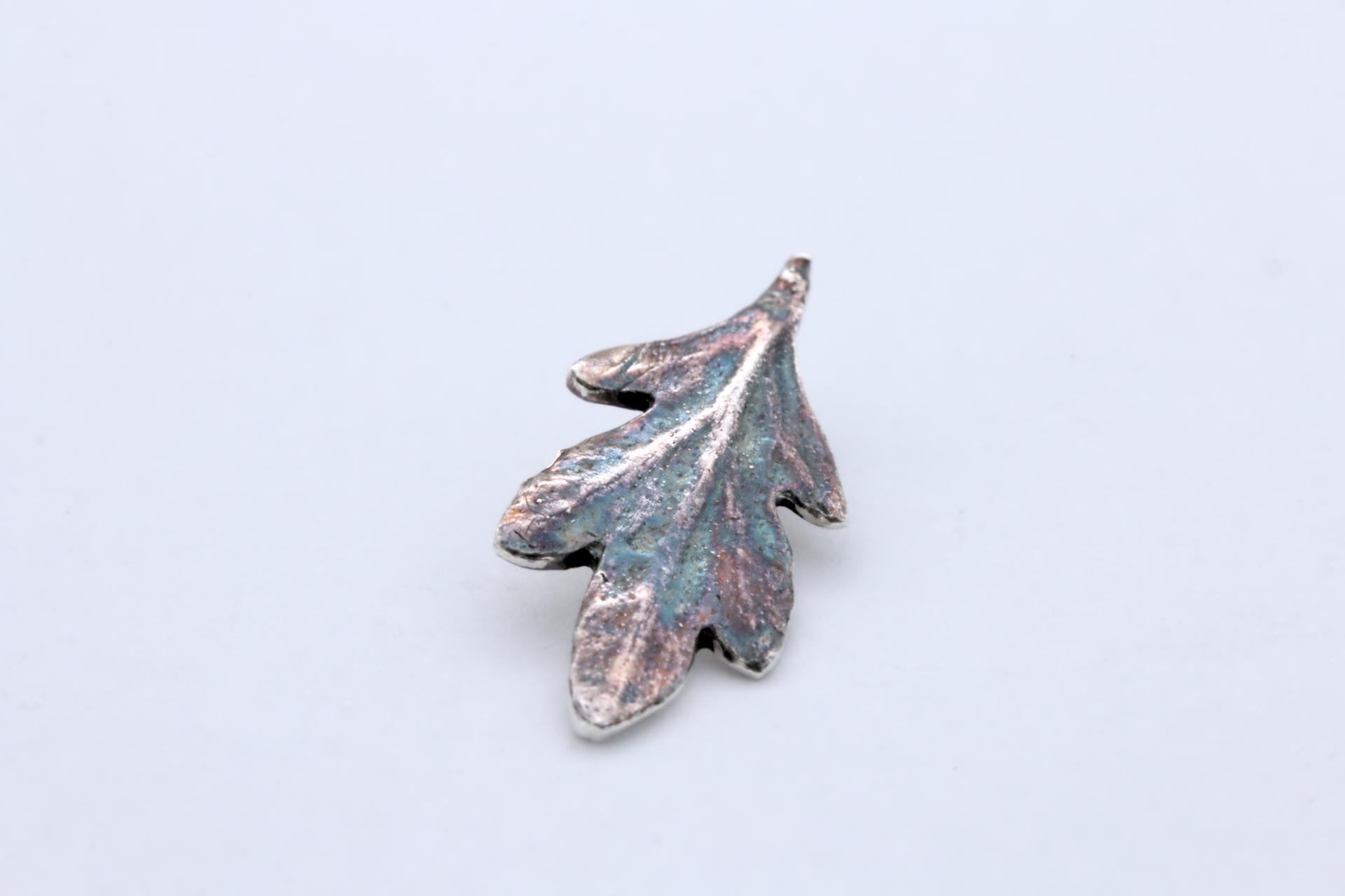 A small silver leaf pendant with colourful patina