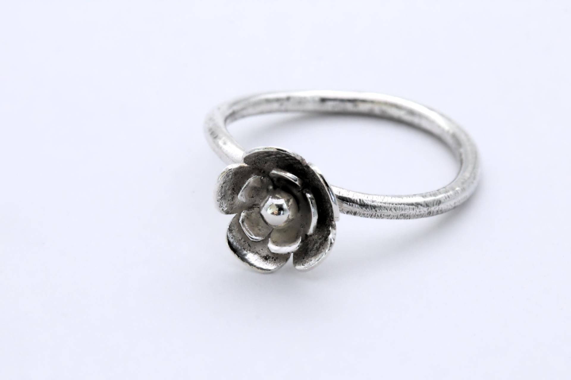 A silver ring with a 3-tier flower