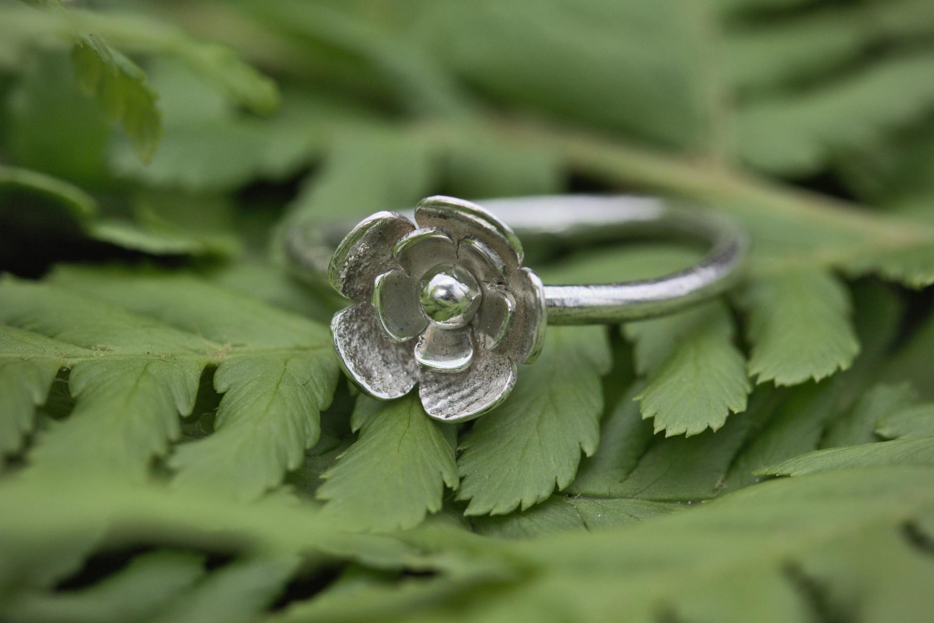 A silver ring with a 3-tier flower