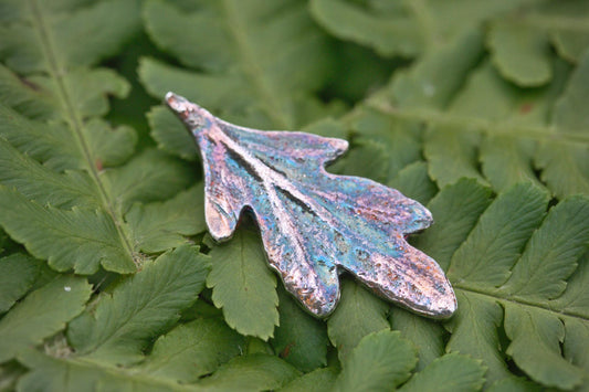 A small silver leaf pendant with colourful patina