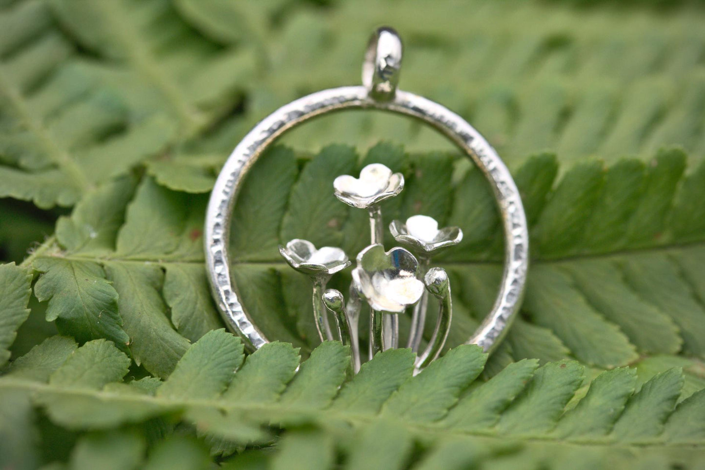 A pendant with multiple tiny flowers within a textured ring